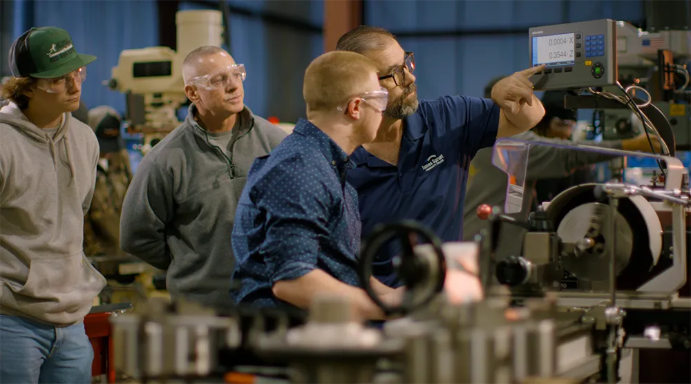 Machine shop teacher instructing students